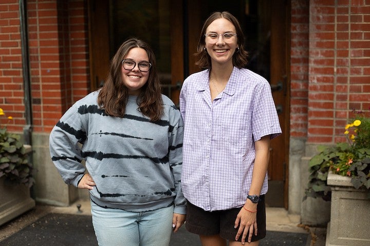 two student tour guides posing in front of Chapman Hall entrance, smiling