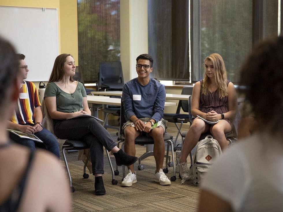 students sitting in circle inside classroom, having a discussion