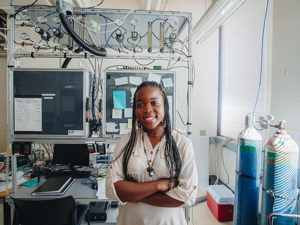 student posing for camera in lab surrounded by equipment