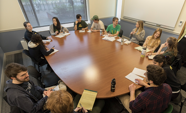 students seated around large classroom table, engaged in partner work