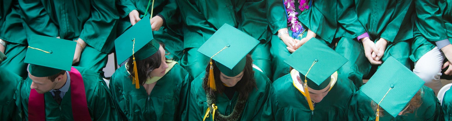 Birdseye view of graduates in green gowns and mortarboard caps.