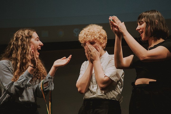 Two students applaud a third at a Forensics Event.