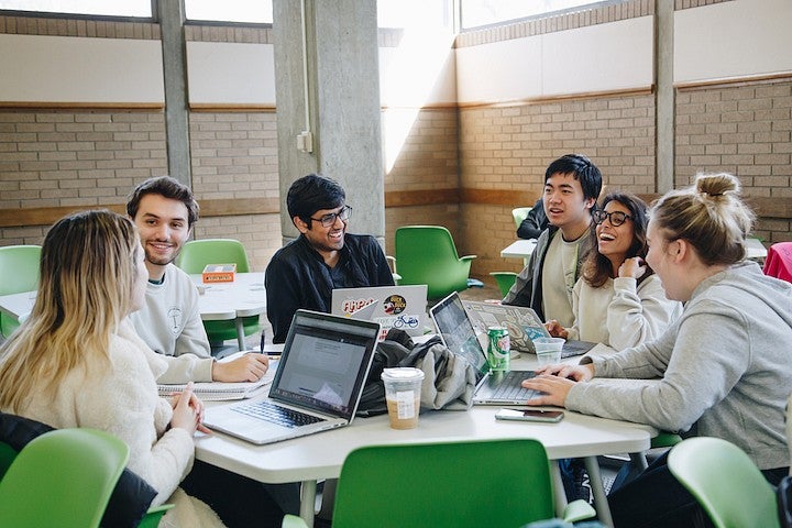 students on forensics team at a table laughing over laptops