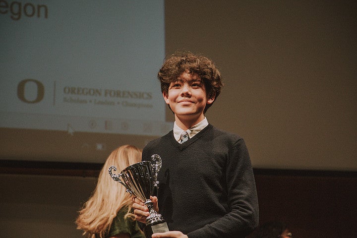 Student at a Forensics Event holding a trophy.
