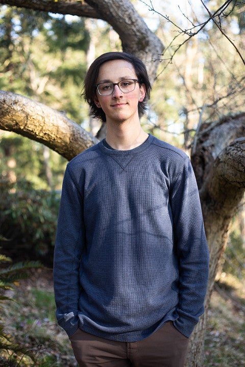 Nathan King standing in front of twisty tree trunks.