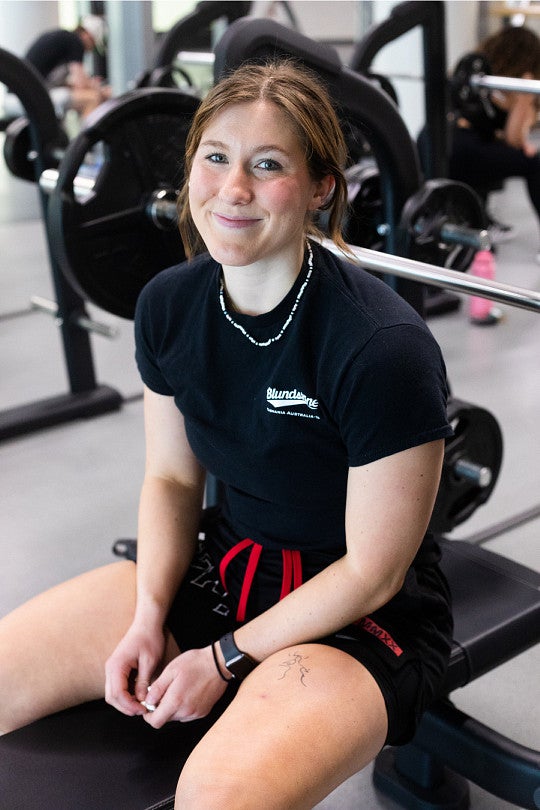 Grace Winjum sitting at a gym station.