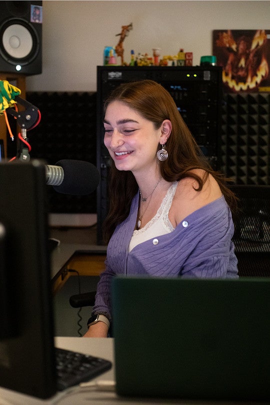 Margo Ladis sits behind DJ equipment.