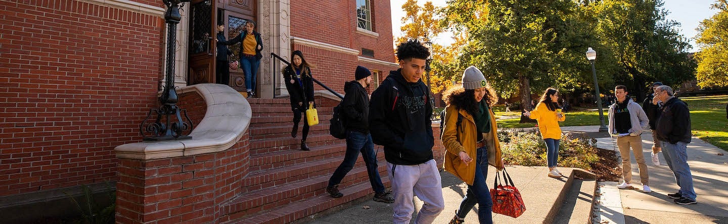students walking down chapman hall exterior stairs into fall morning light