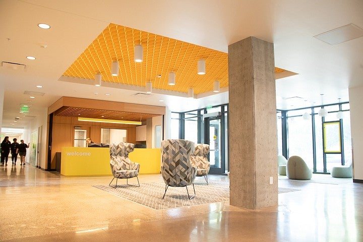 lobby of the new residence hall, with floor to ceiling windows, armchairs and a welcome desk