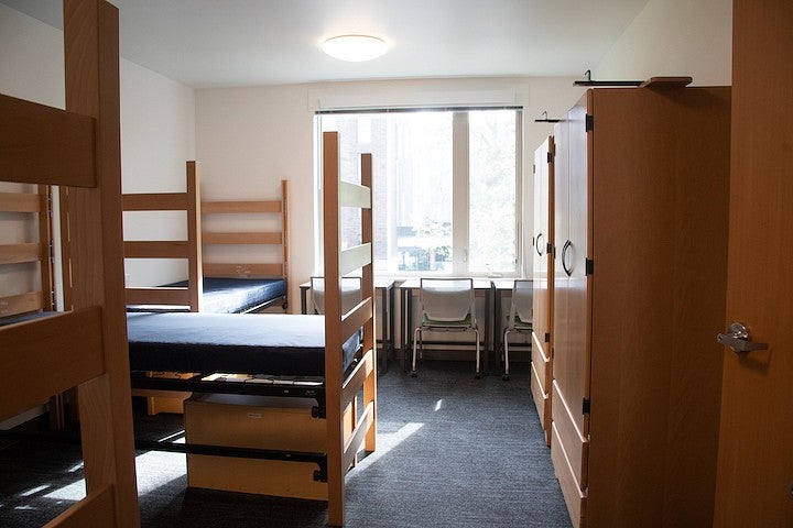 inside a vacant triple room in the new residence hall. with three beds, desks and armoires
