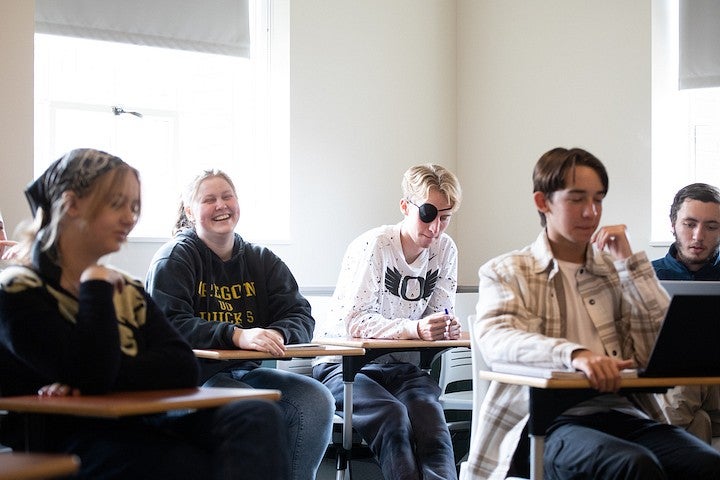 students in classroom desks, smiling and laughing