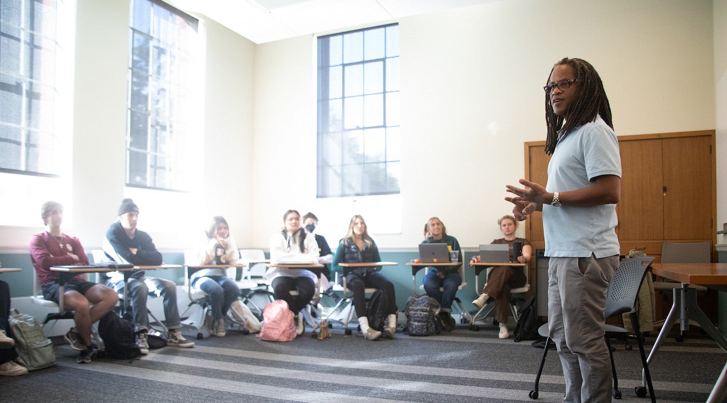 Ulrick Casimir standing in front of sunlit classroom teaching a group of students