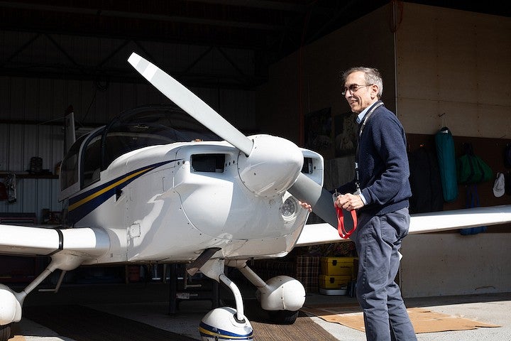 robert mauro touching propellor of small plane parked in hangar