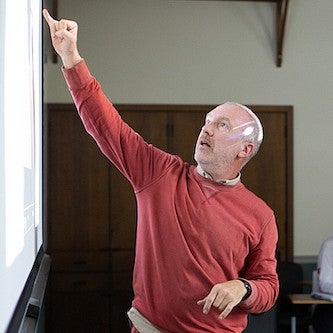 christopher michlig pointing at the board as he teaches a class