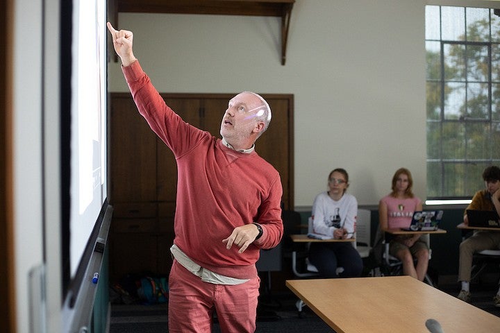 christopher michlig pointing at the board as he teaches a class