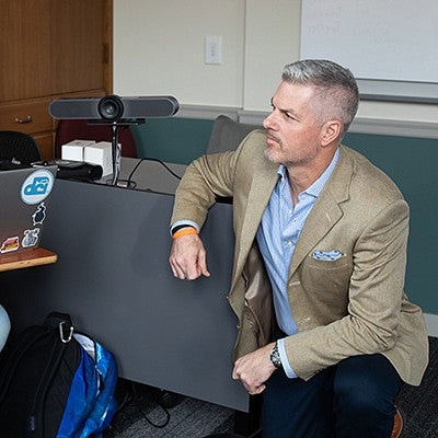 tobin hansen takes a knee in front of a student's desk during a class discussion