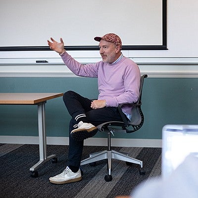 professor chris michlig sitting at front of class, gesturing during a discussion
