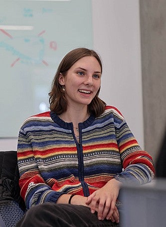 active portrait of Mia Owen conversing with someone off camera, seated in a classroom