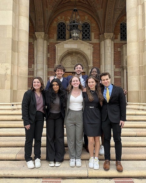 group of students in business attire posing on steps of ornate stone building