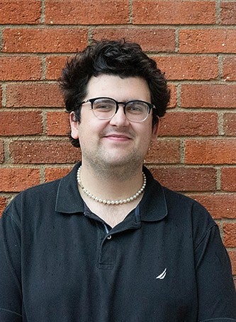 portrait of student evan reynolds in front of brick wall