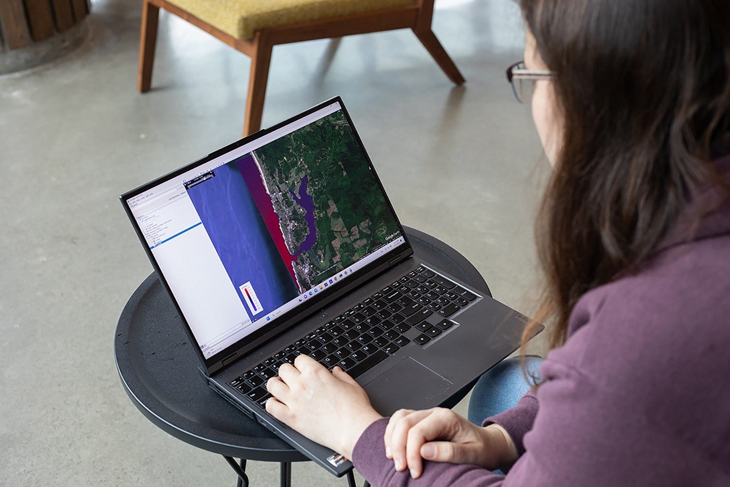 looking over a student's shoulder at their laptop screen, showing a visualization of the west coast with tsunami intensity indicated in red