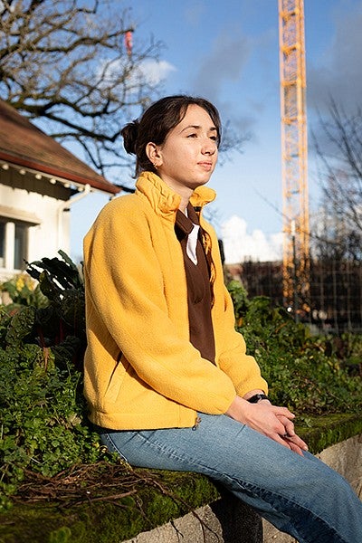 portrait of student Keaton Ibendahl sitting on wall at urban farm on a sunny winter day