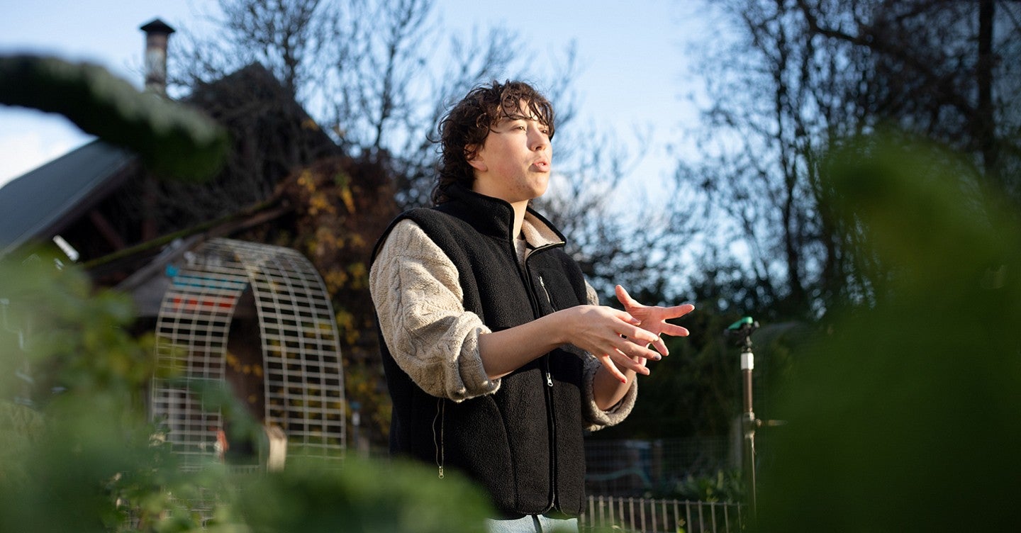 a person talking and gesturing standing amid a garden bed on a sunny winter day