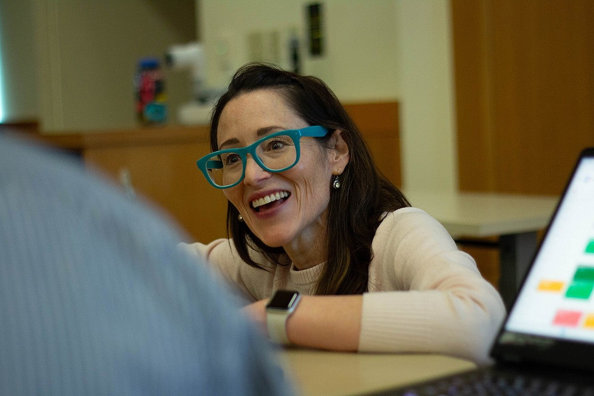 professor hannah cutting-jones talking to students across a table in the classroom