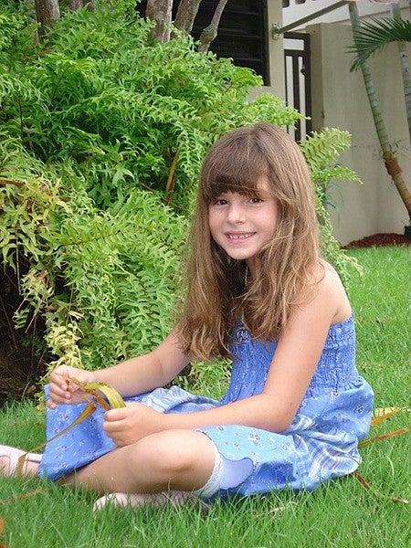 girl child sitting in grass, smiling