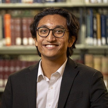 portrait of kavi shrestha in front of a bookshelf