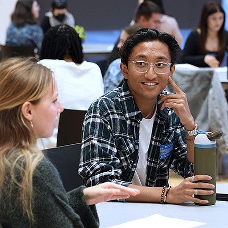 students sitting at round tables, talking and listening to one another