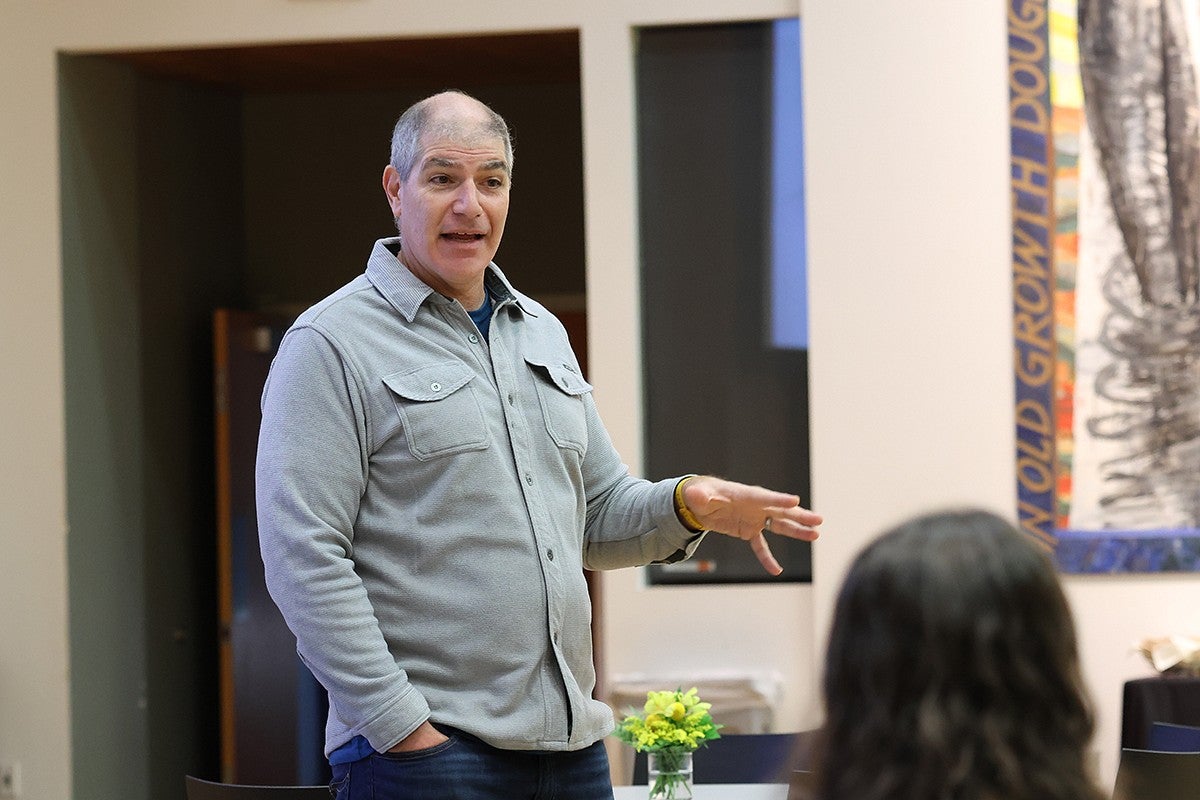 faculty member standing and speaking to a room of people seated at tables