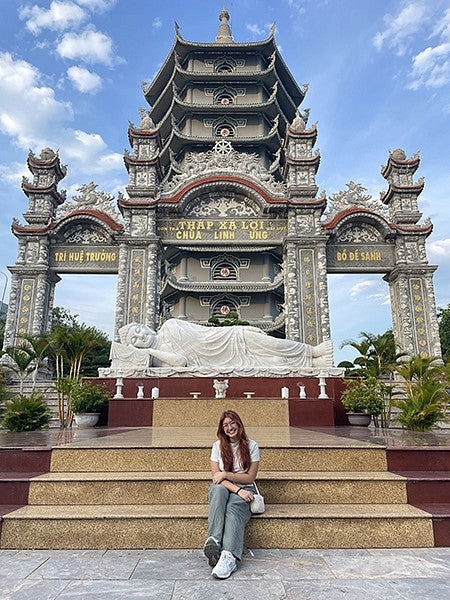 dante sitting on steps of shrine with reclining buddha