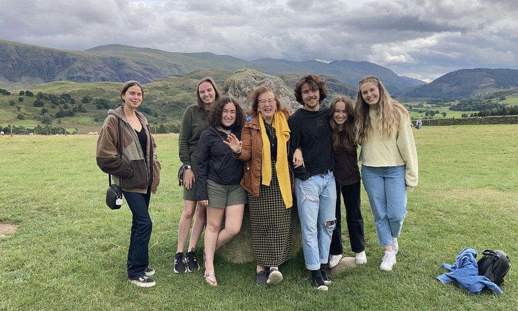 group of people posing in front of standing stone in english countryside