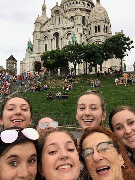 group of women taking selfie in front of cathedral on hill