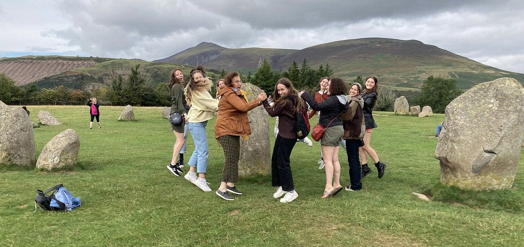 group of people circling around a standing stone in the oxford countryside