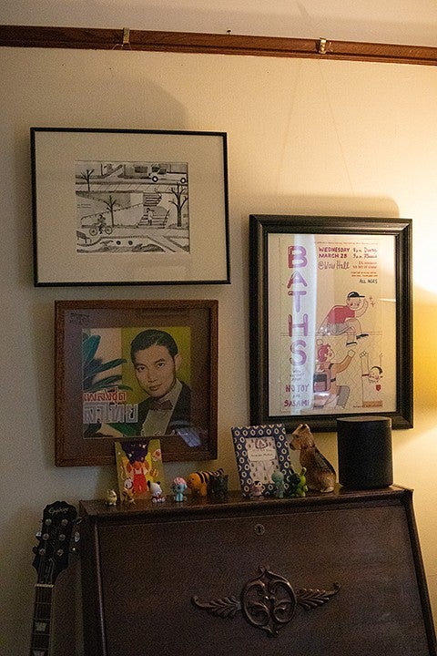 framed art hanging on a wall above a dresser with figurines lining the top