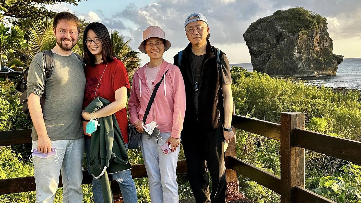 vacation photo of deborah wang, her parents and boyfriend posing with oceanscape and rocky island in background