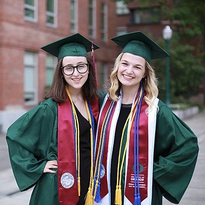 graduation portrait of two young women together in cap and gowns
