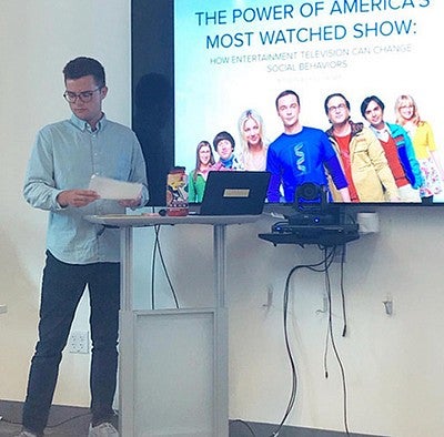 kyle heiner in front of presentation screen defending his thesis about The Big Bang Theory