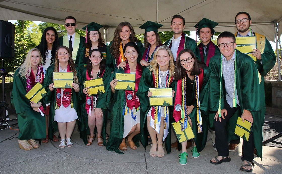 a group of students in graduation regalia, holding diplomas