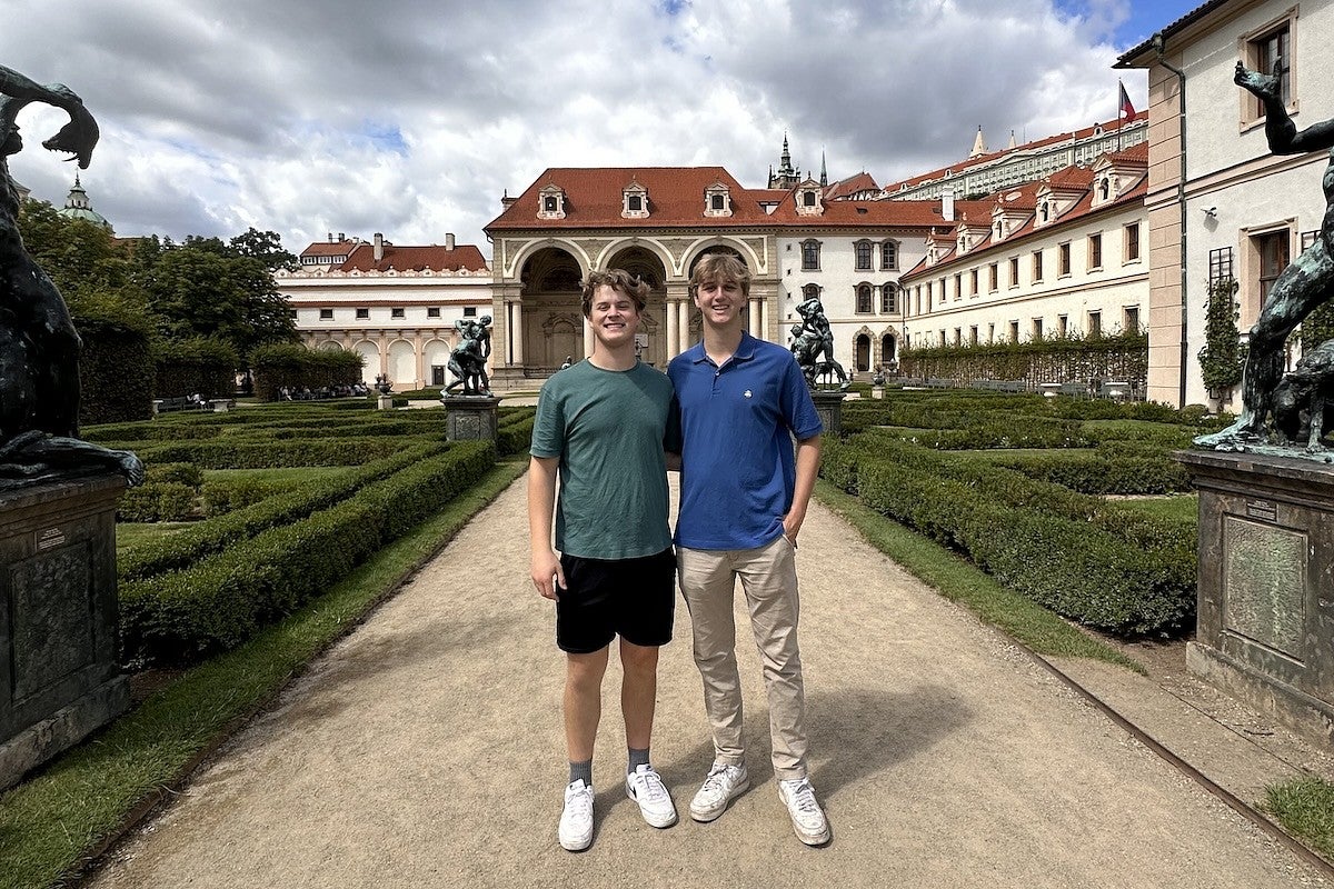 two students posing in a formal garden surrounded by historic buildings in germany