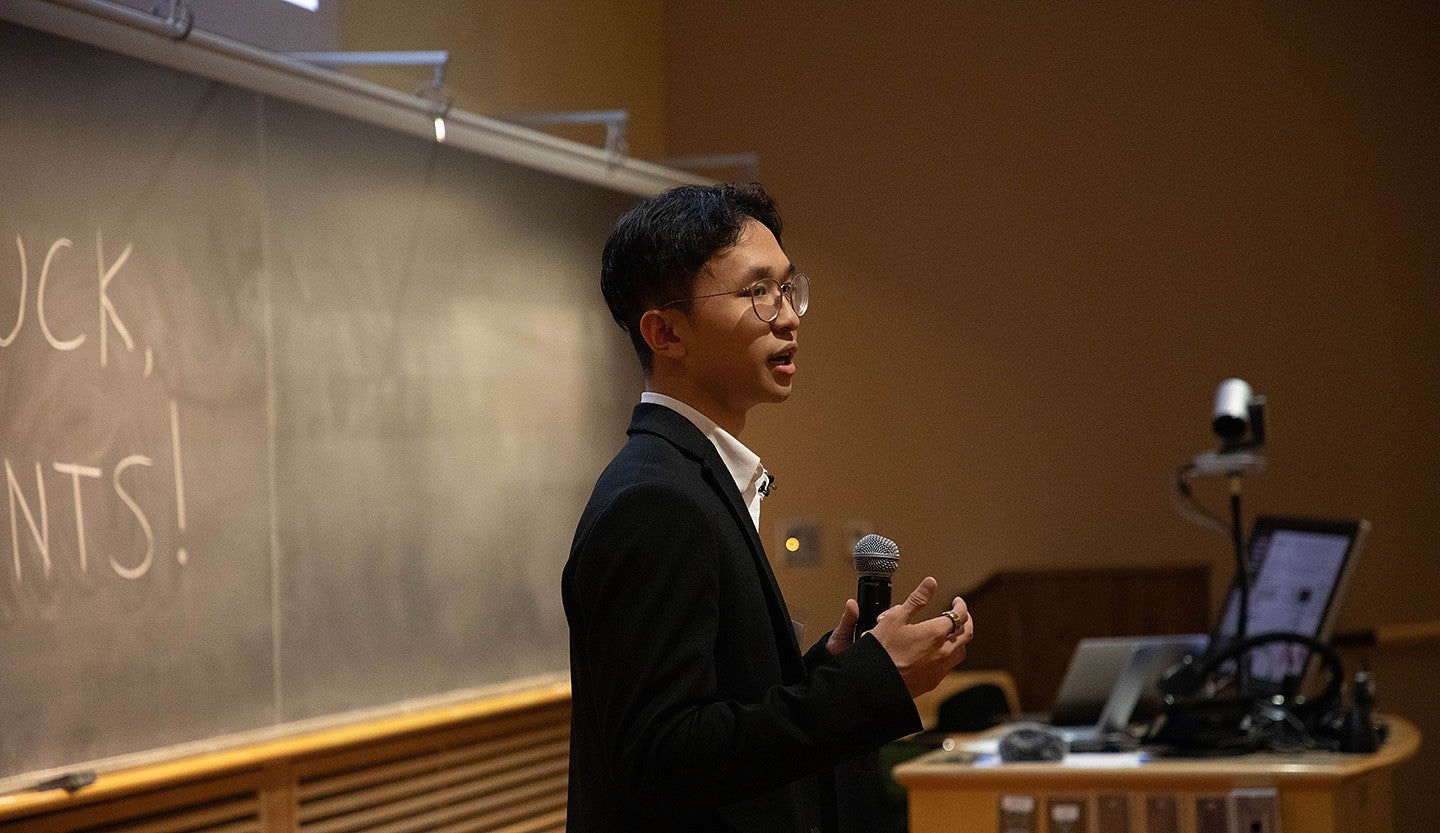 student speaking into microphone at front of lecture hall