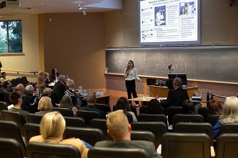 student presenting to audience with digital projector and microphone