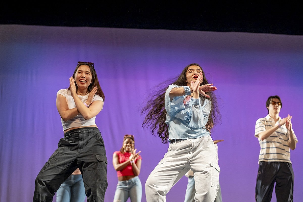student gayatri misra and other students dancing on stage in front of purple background