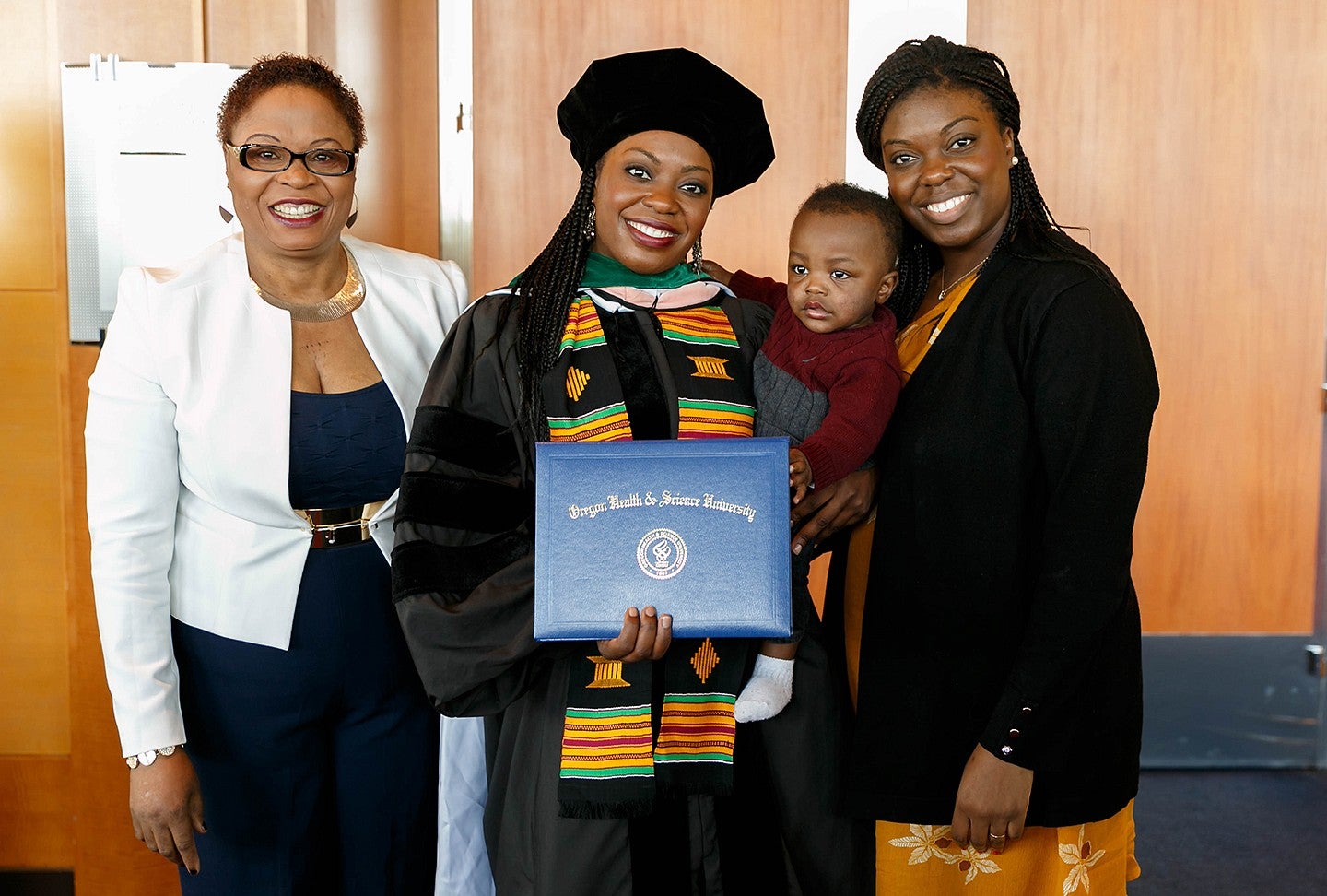 ann oluloro in regalia at her graduation from OHSU posing with her mother, sister snd nephew 
