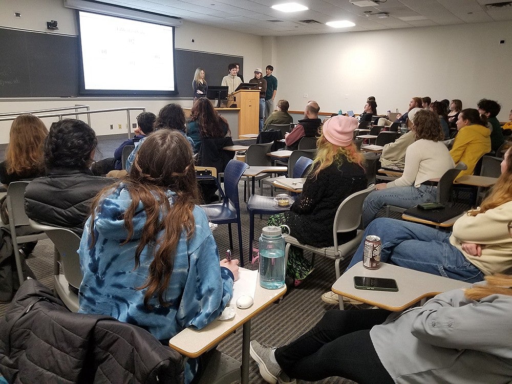 a room full of students watching a student presentation