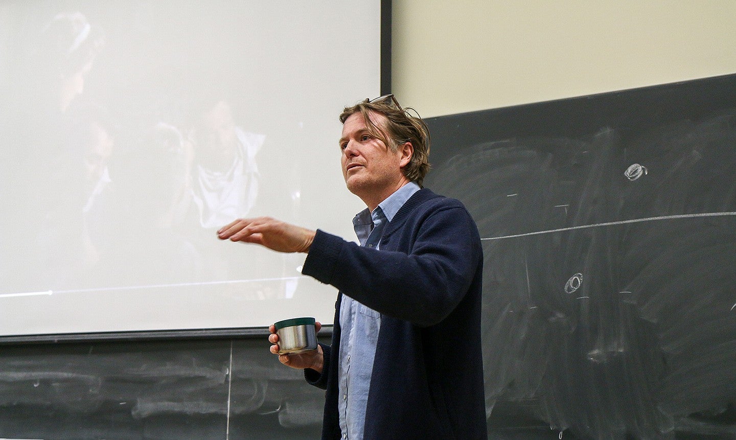 chc professor casey shoop teaching at front of classroom with thermos in hand