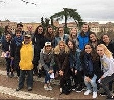 group of students posing with Siena, italy cityscape in background