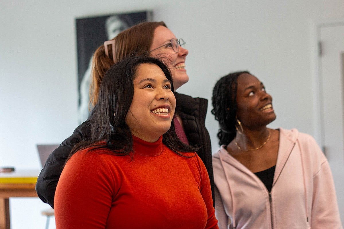 students standing together in campus building, smiling